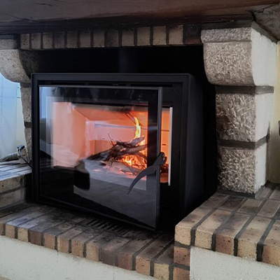 Insert à bois encastré dans une cheminée en pierre